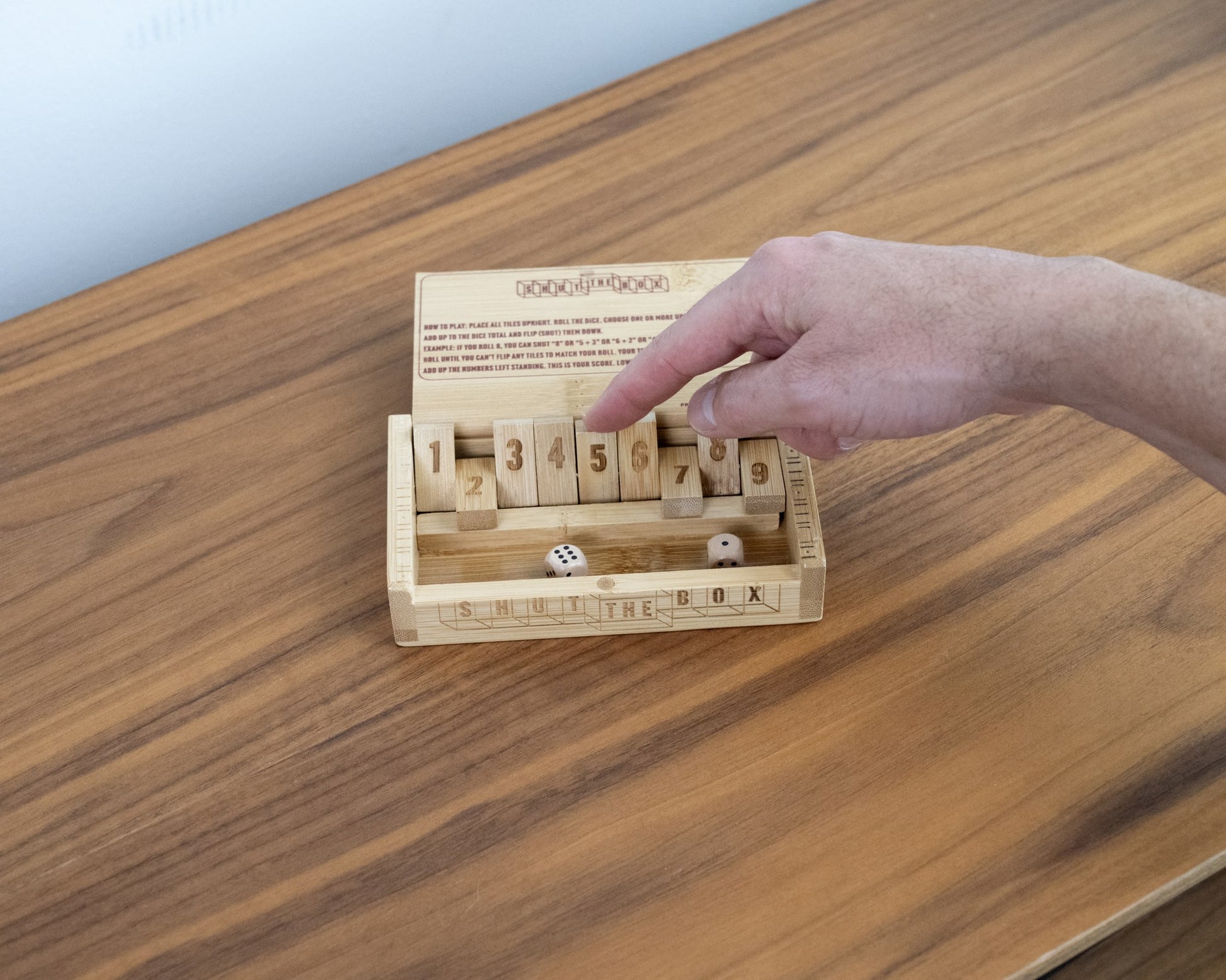 Shut the Box bamboo dice game being played on a wood table